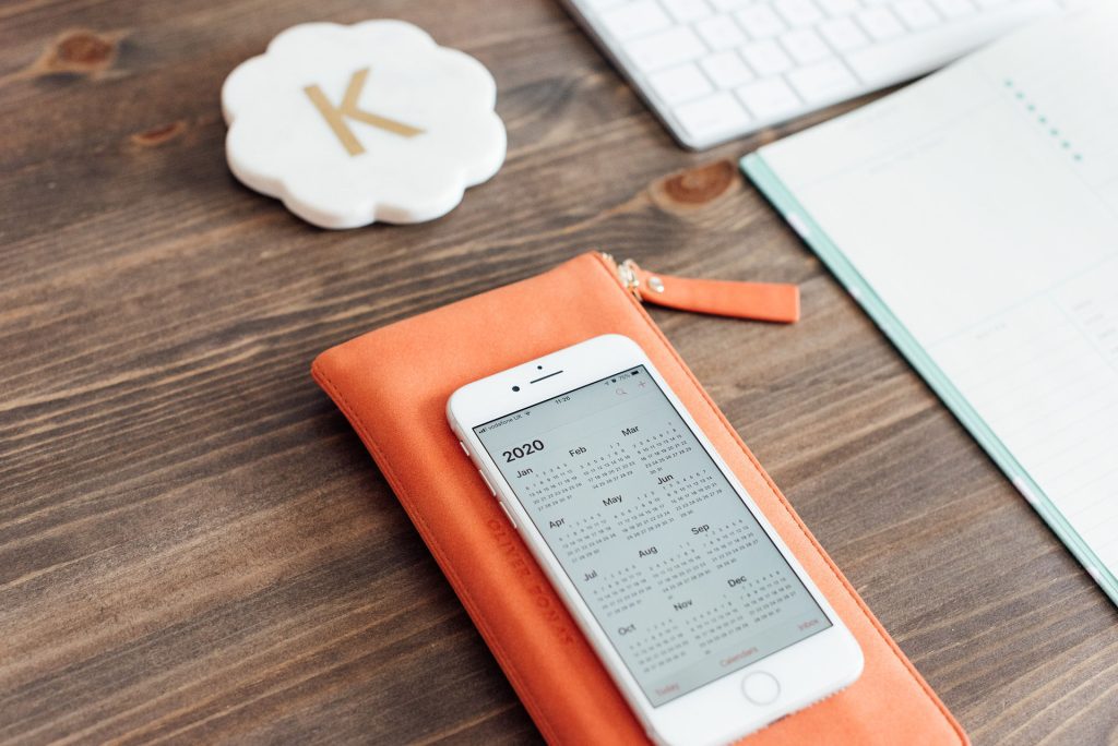 Desk with iphone showing 2020 calendar and daily planner