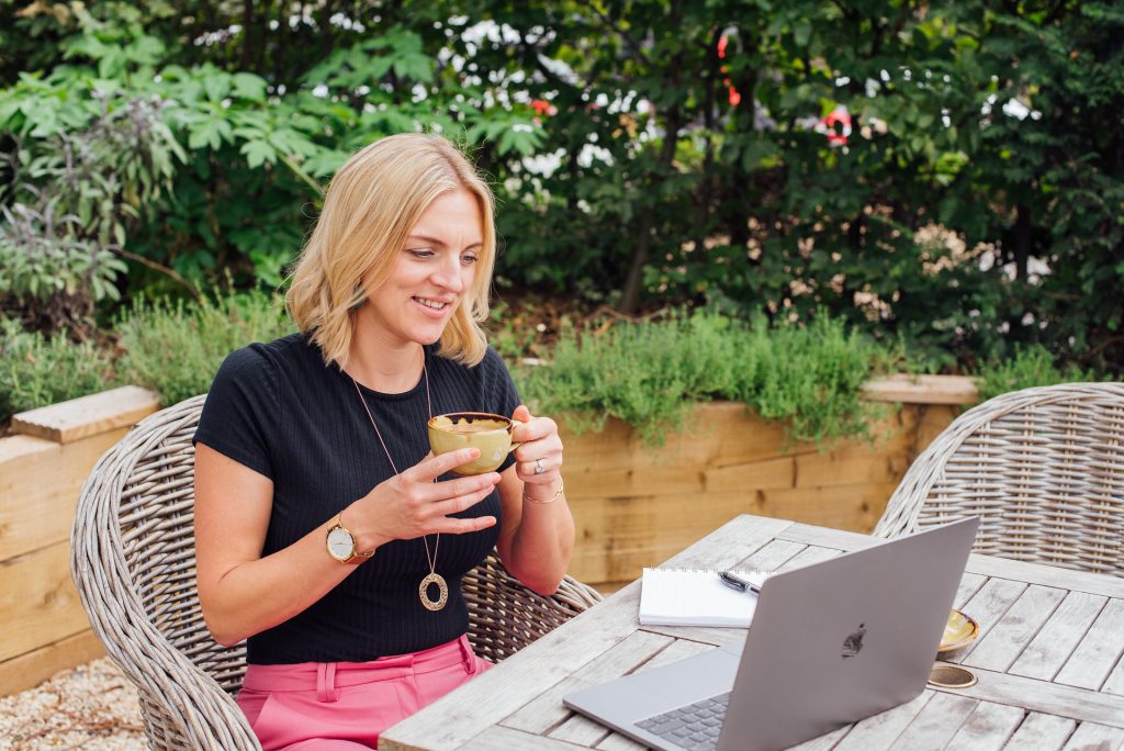 Woman sat drinking tea looking at laptop