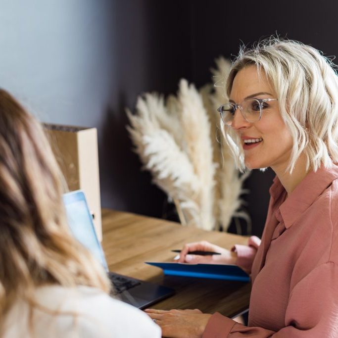 Kellie in red and glasses coworking with colleague.
