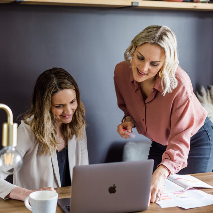 Colleague at a desk working, Kellie overseeing work.