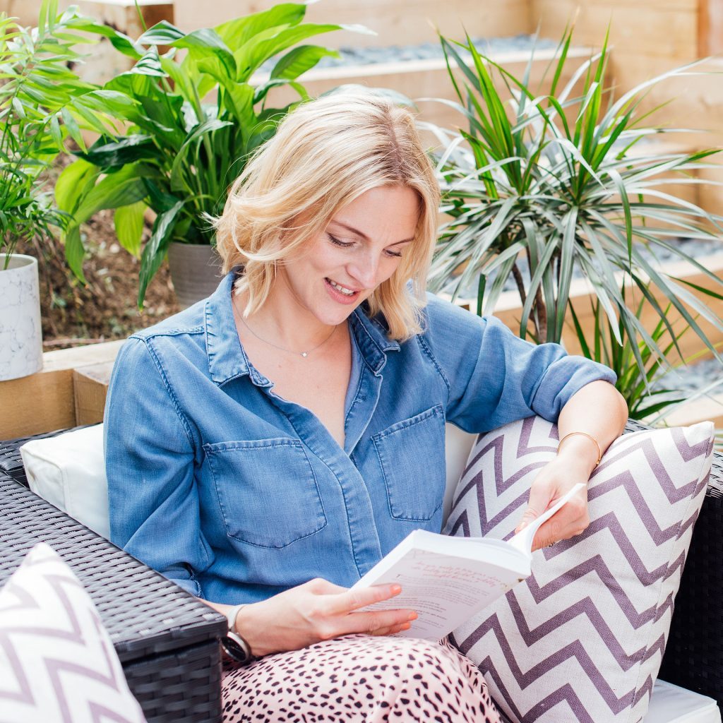Woman in garden reading book in Summer