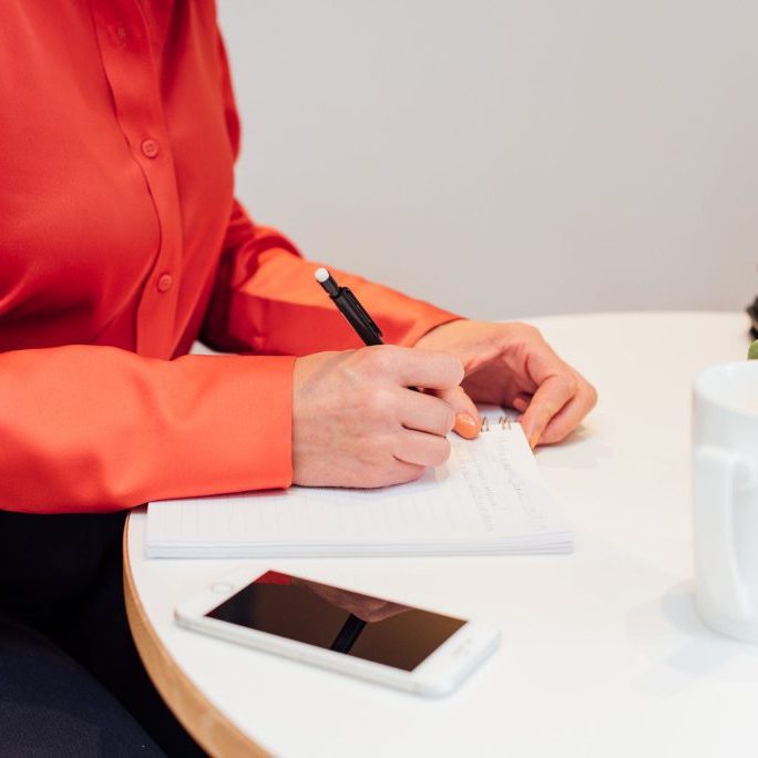 Lady sat at table with a notebook and phone planning for an event.