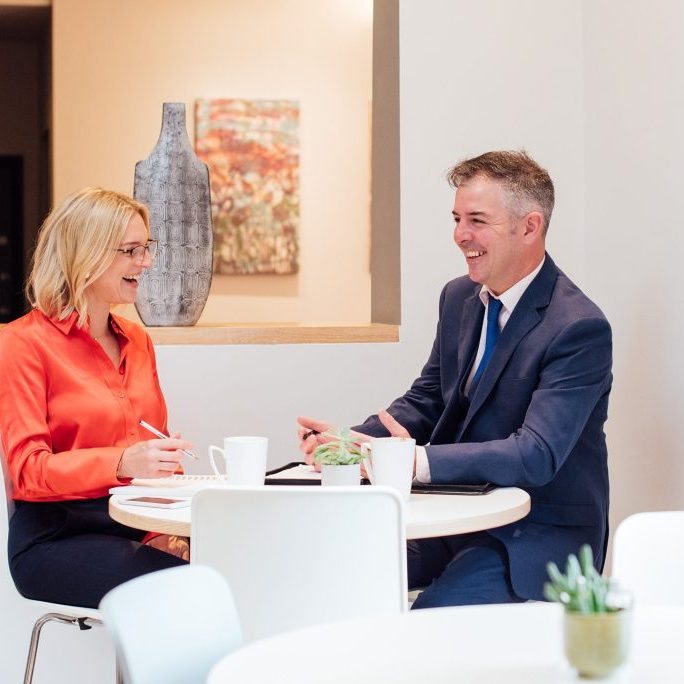 man and woman sat at a table chatting.