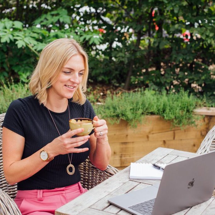 Woman sat drinking tea looking at laptop
